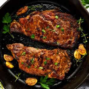 Marinated cooked steaks in a cast iron skillet.