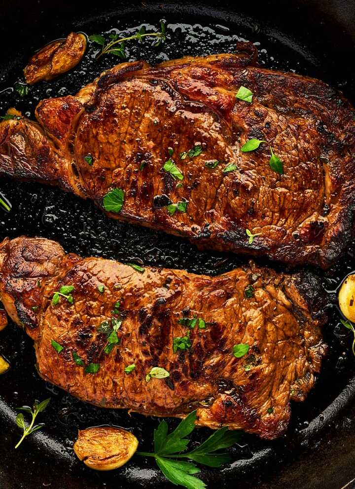 Marinated cooked steaks in a cast iron skillet.