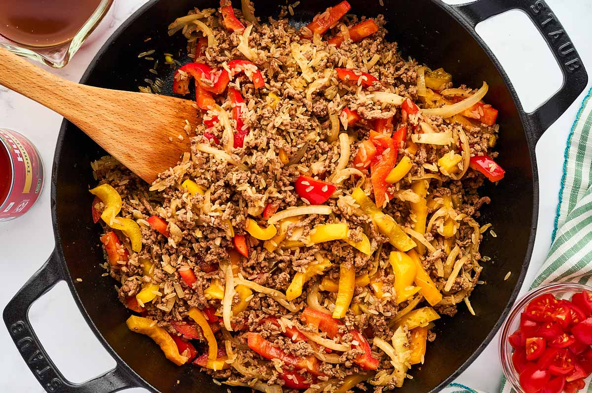 Ground beef, onions, rice and peppers in skillet.