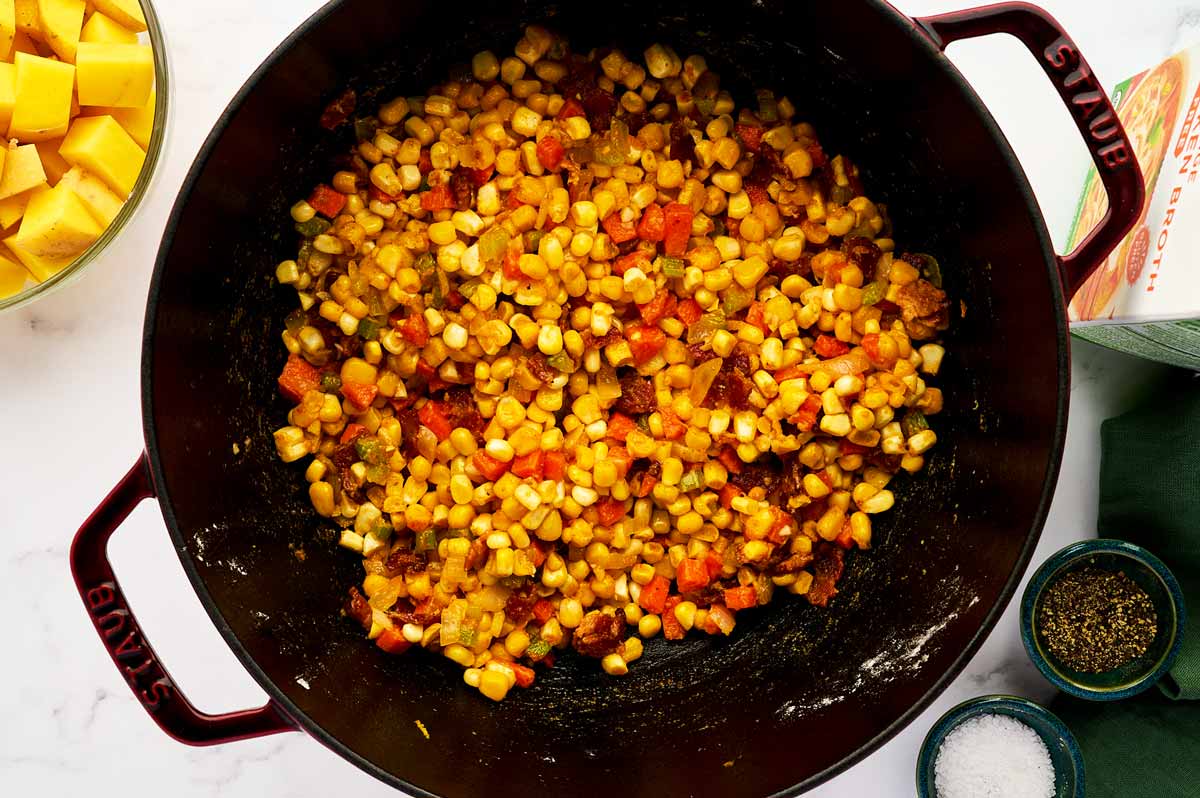 Sautéing vegetables in a cast iron pot with BBQ seasoning.