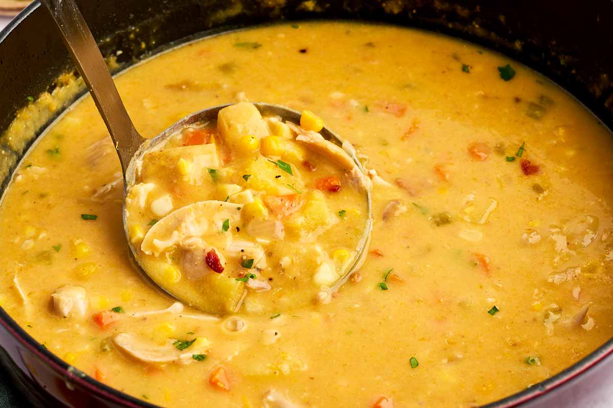 Ladling chicken and corn chowder from a pot.