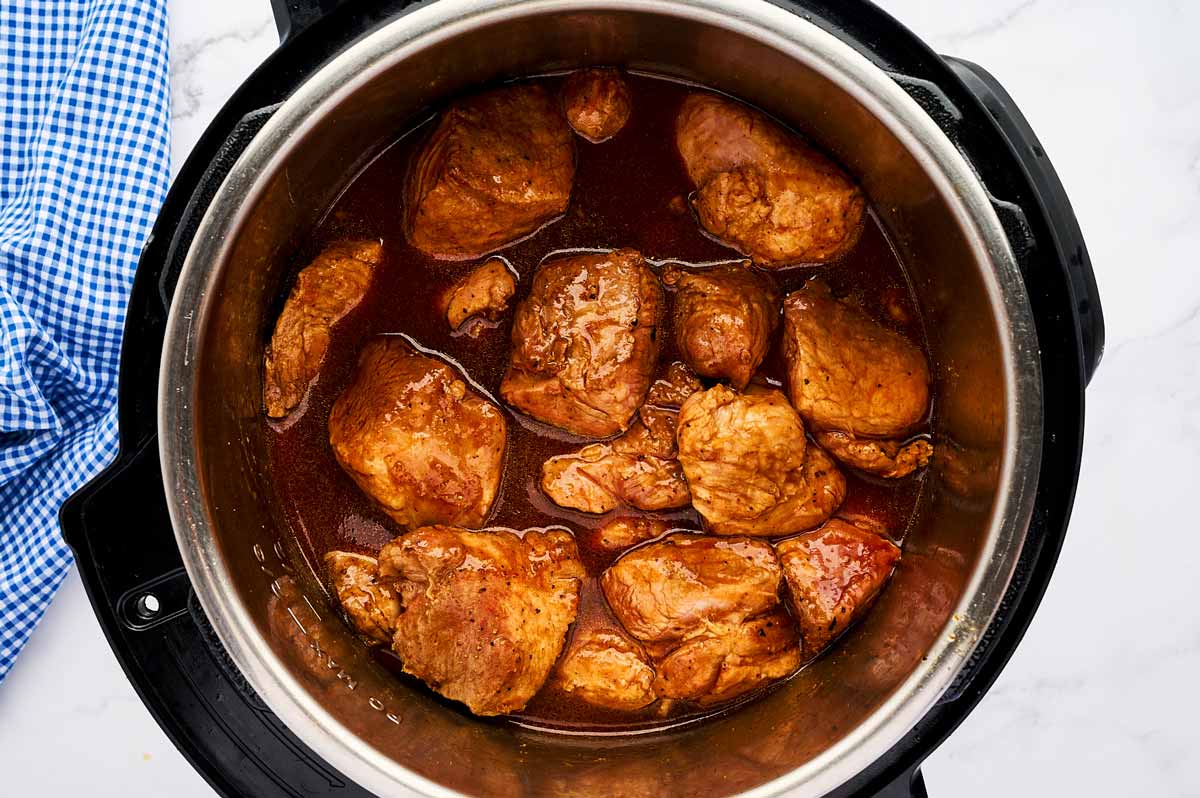 Uncooked pork in BBQ sauce in instant pot.