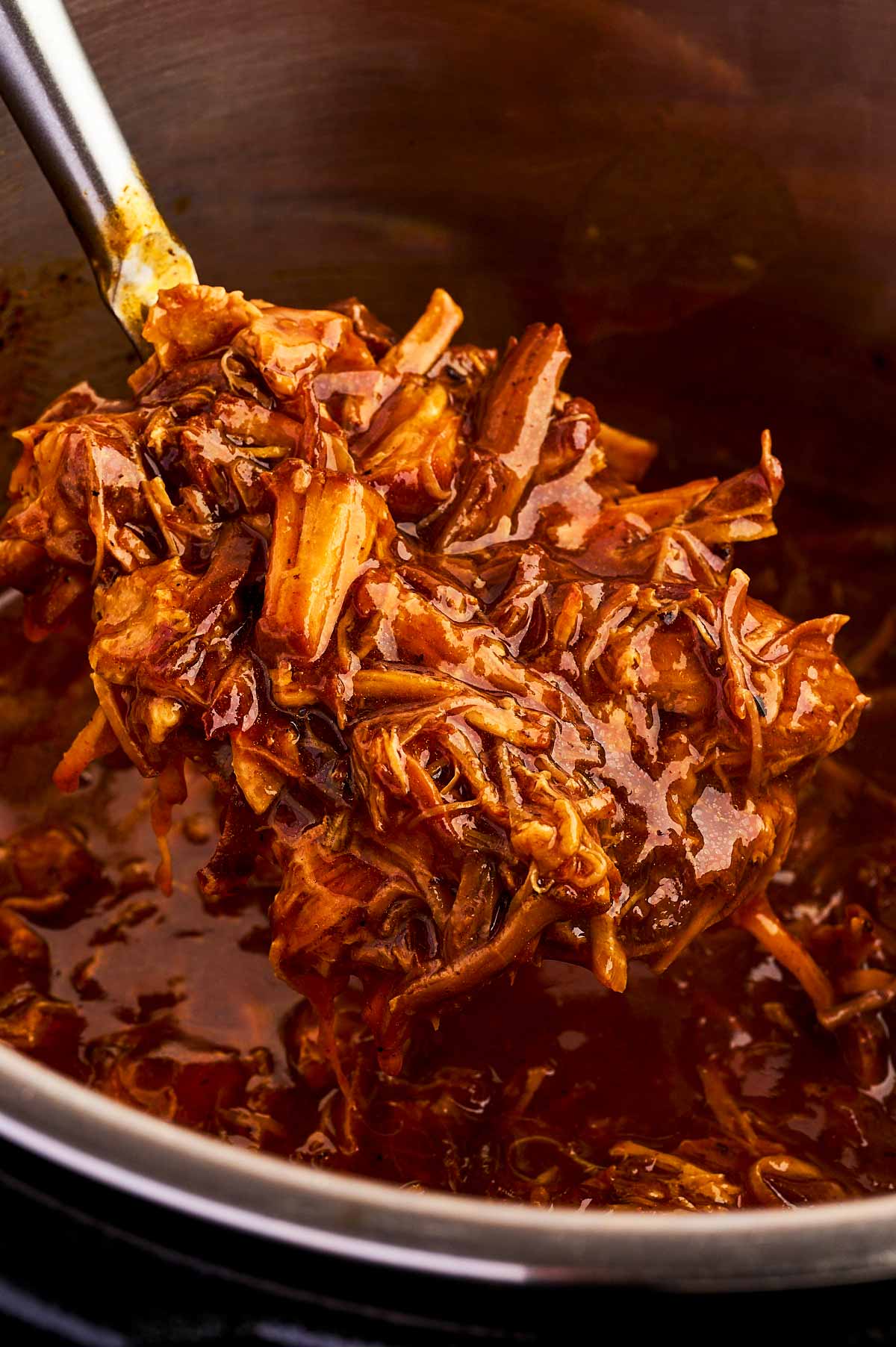 Close up photo of a spoon with honey bbq instant pot pulled pork.