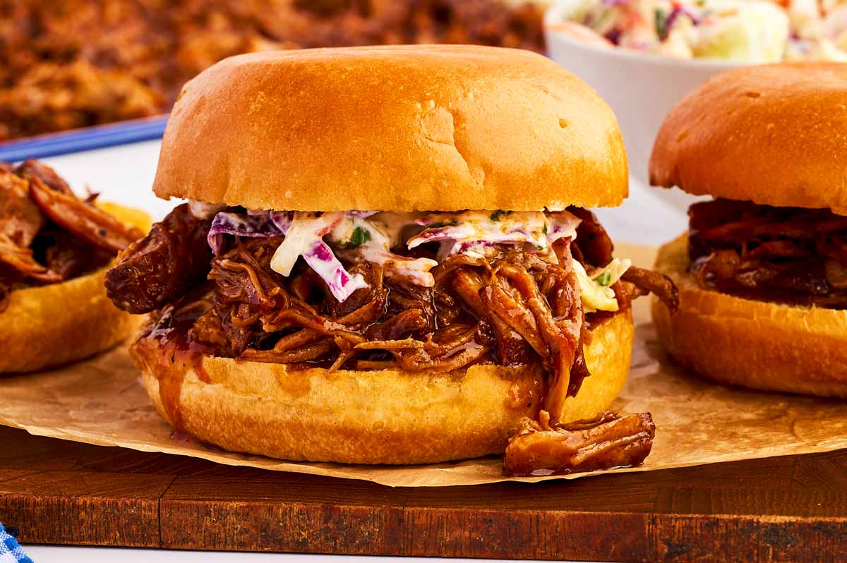 Pulled pork sandwich on a wooden platter.