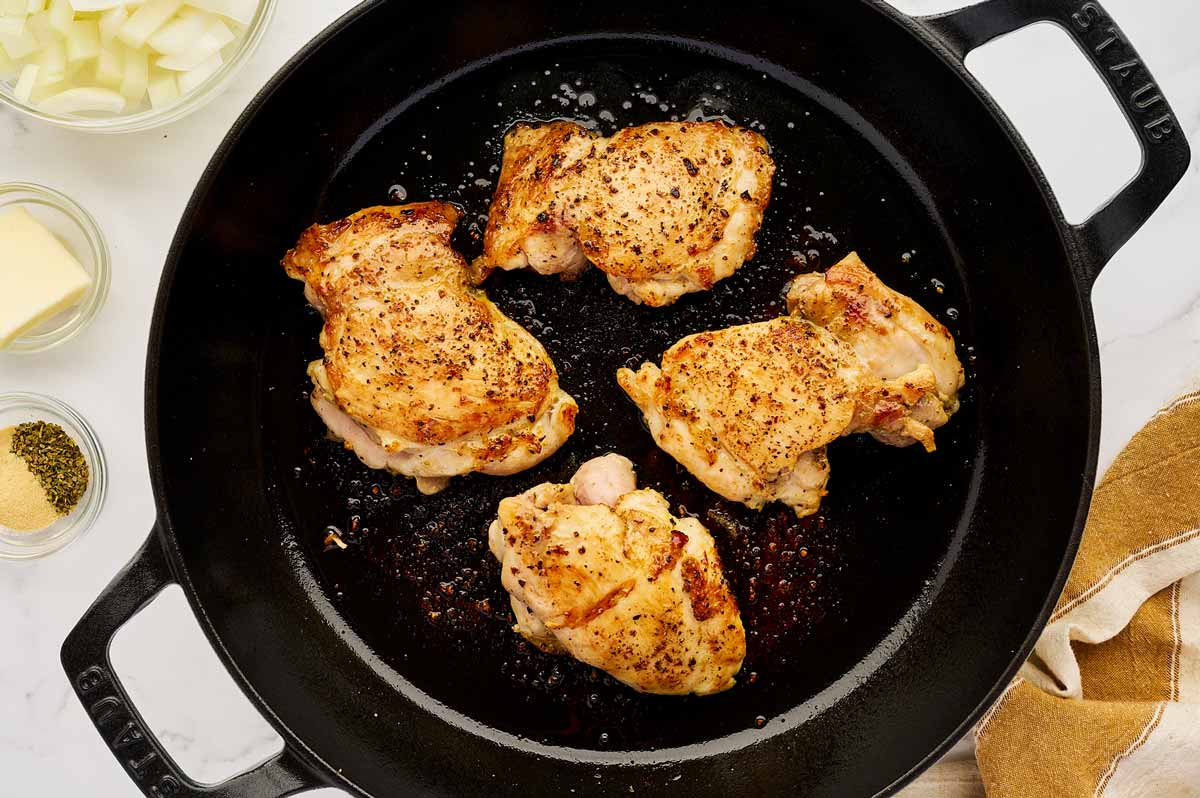 Seared chicken thighs in a cast iron skillet.