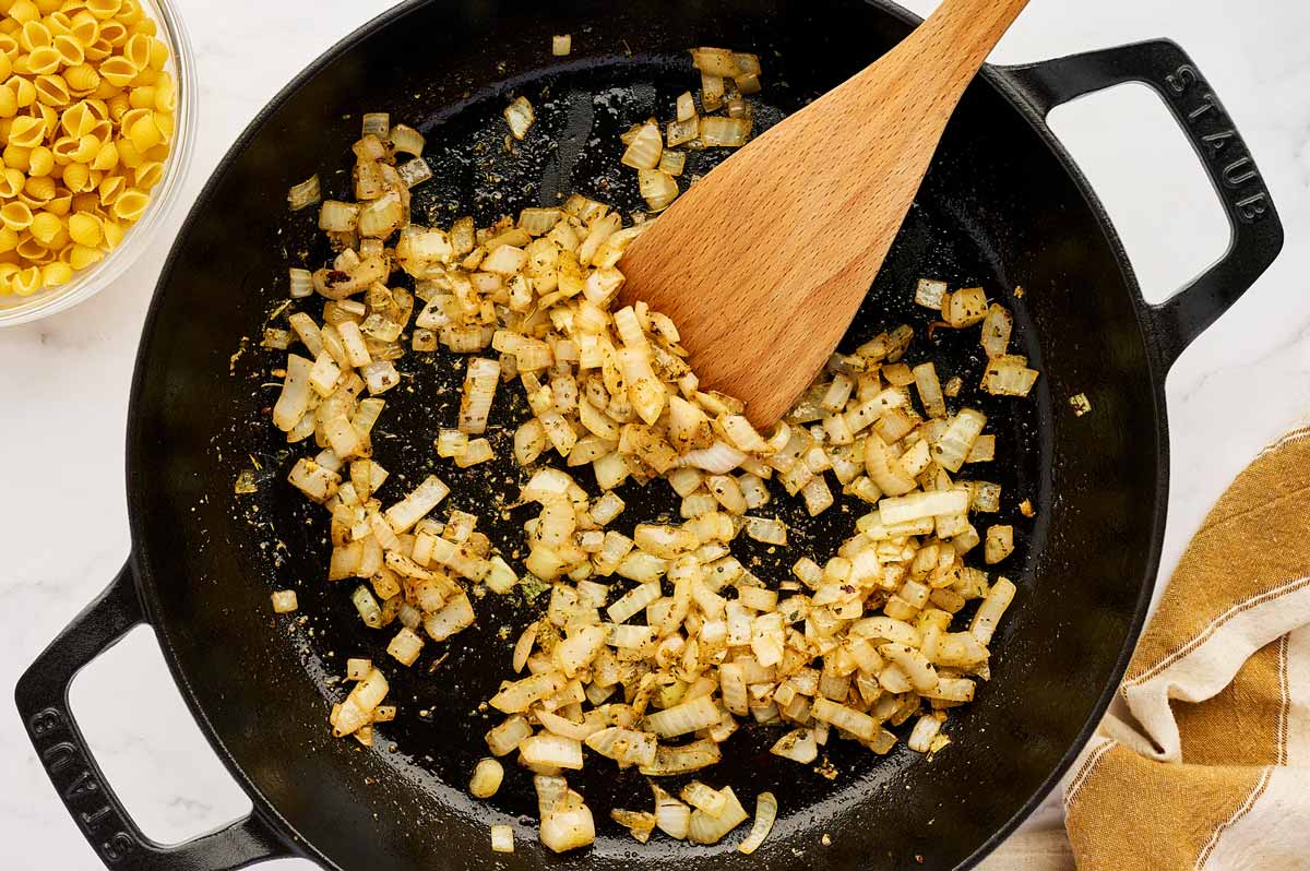 Sautéed onion in cast iron skillet with a wooden spoon.