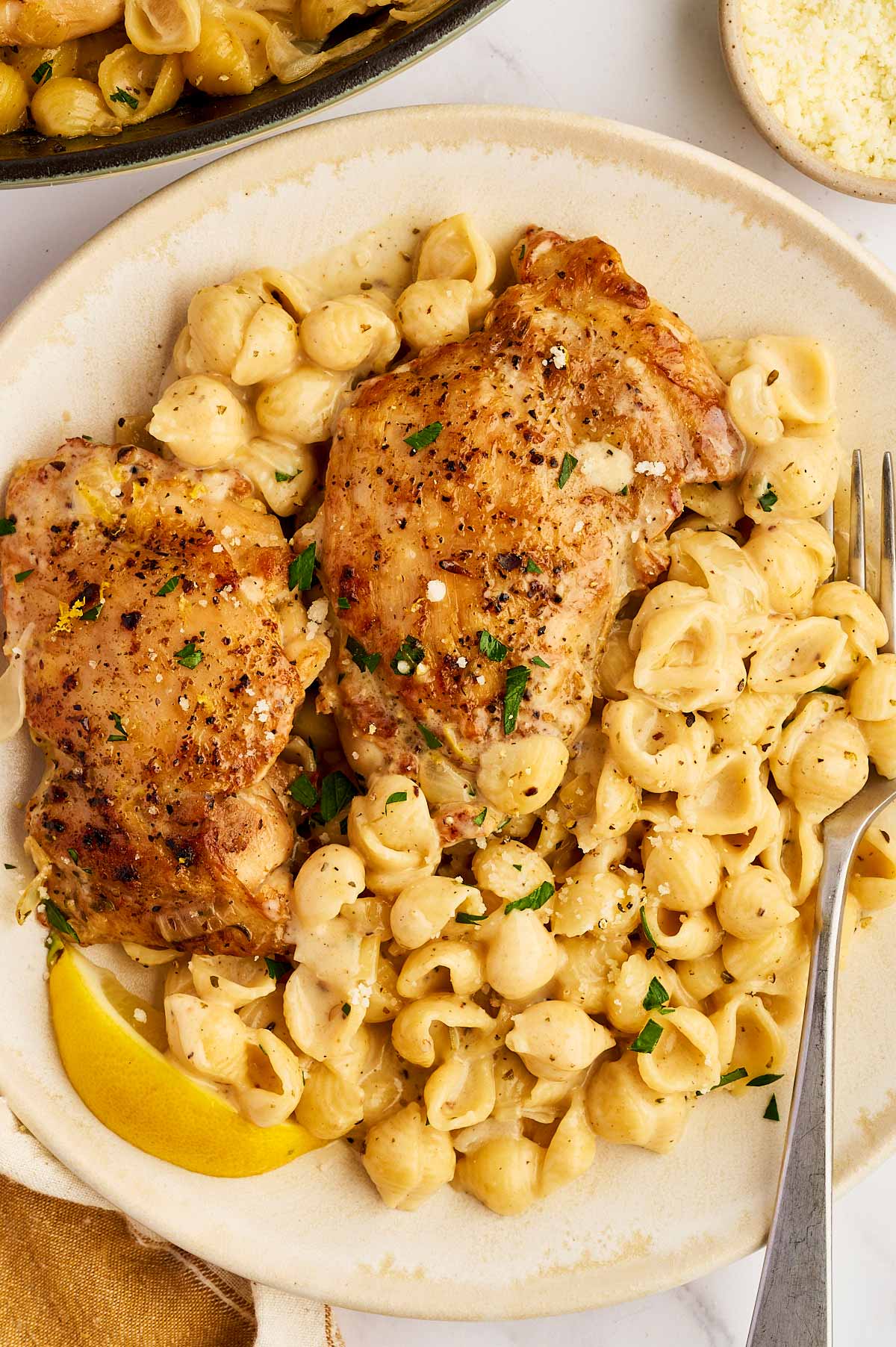 Plate with creamy pasta and seared chicken thighs.