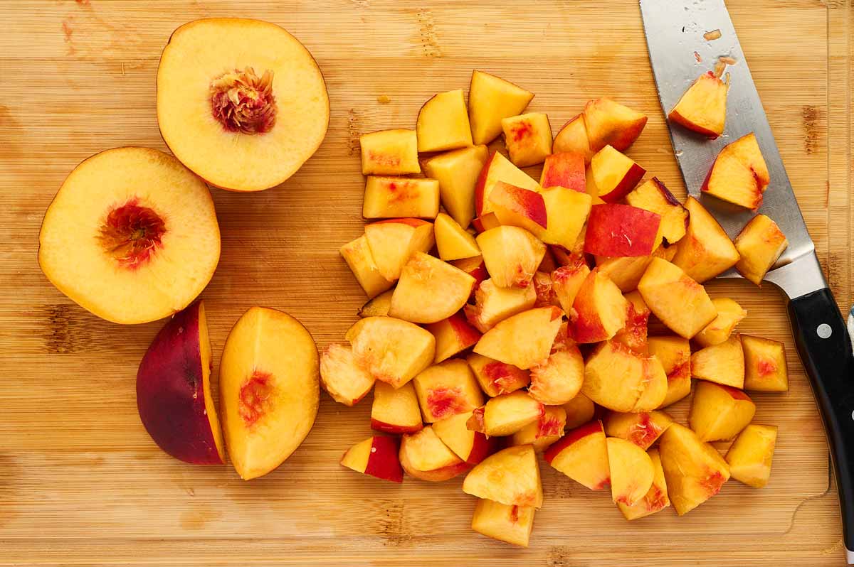 Cut up peaches on a wooden cutting board.