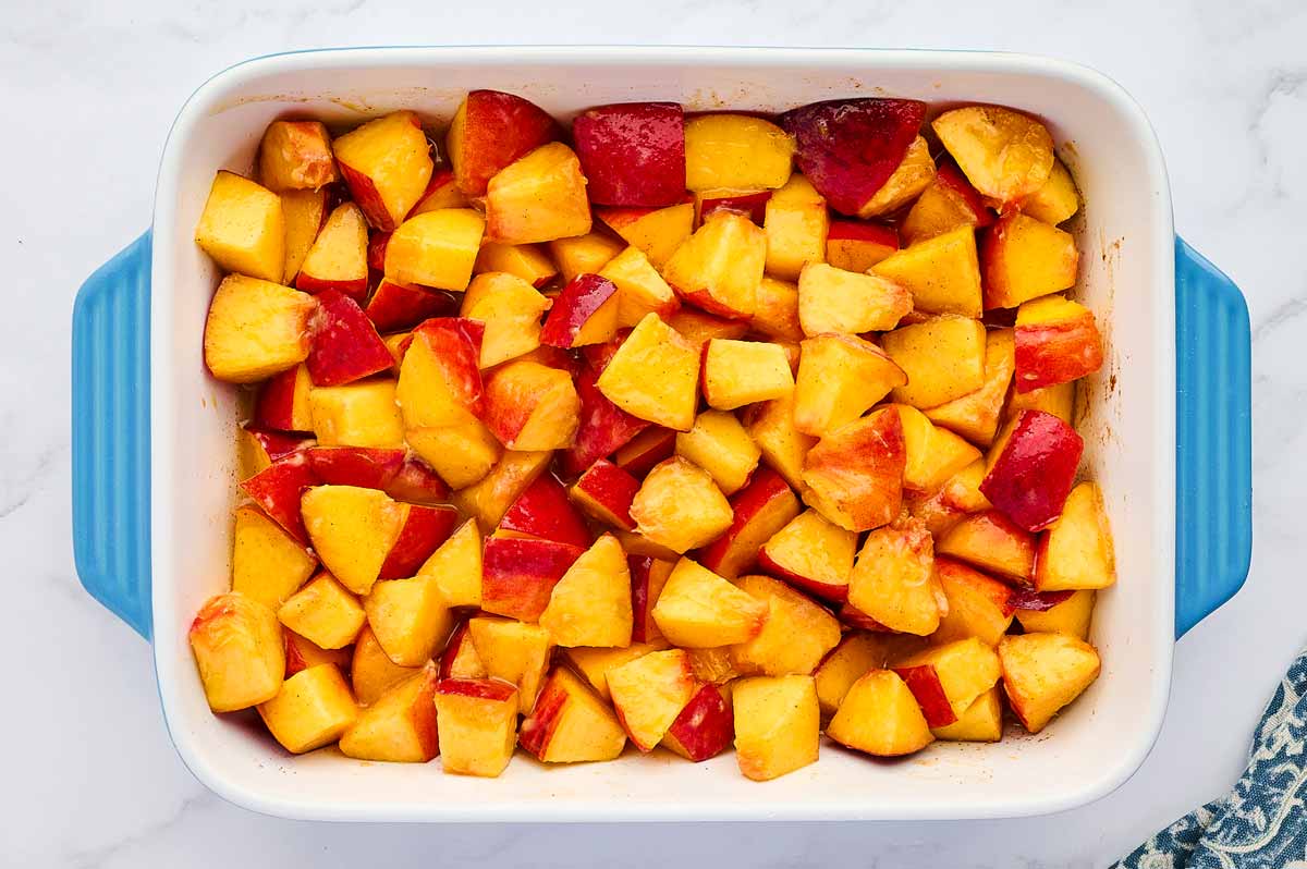 Peach crisp filling in a casserole dish.