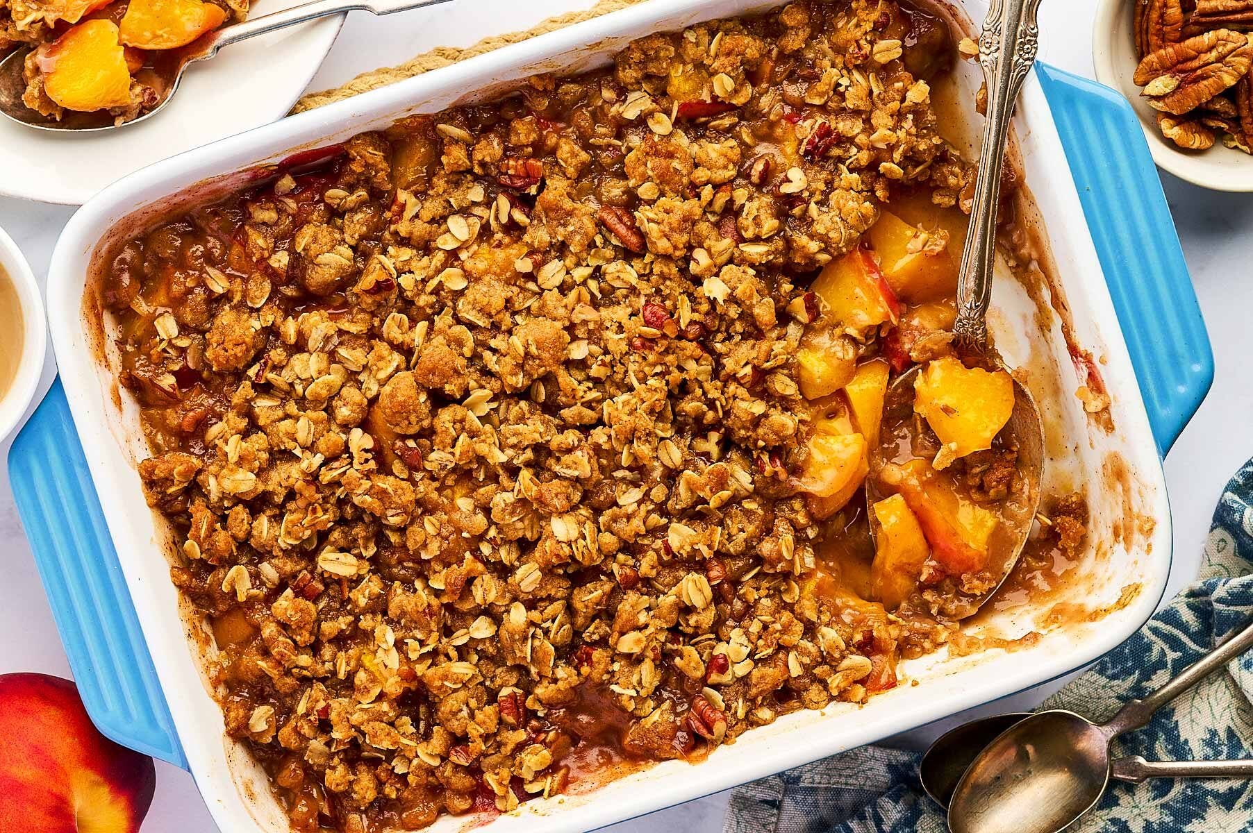 Overhead view of peach crisp in a blue casserole dish.
