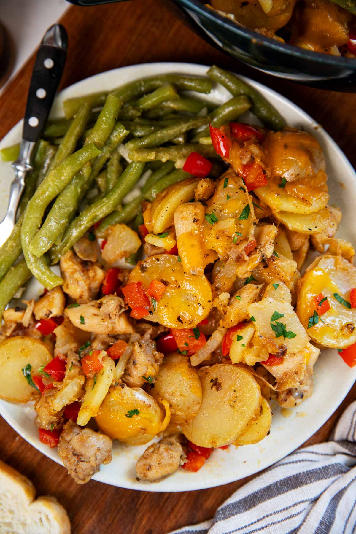 Plate with green beans, cajun chicken and potatoes and buttered bread on the side.