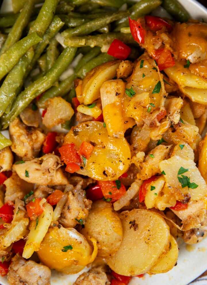 Plate with green beans, cajun chicken and potatoes and buttered bread on the side.