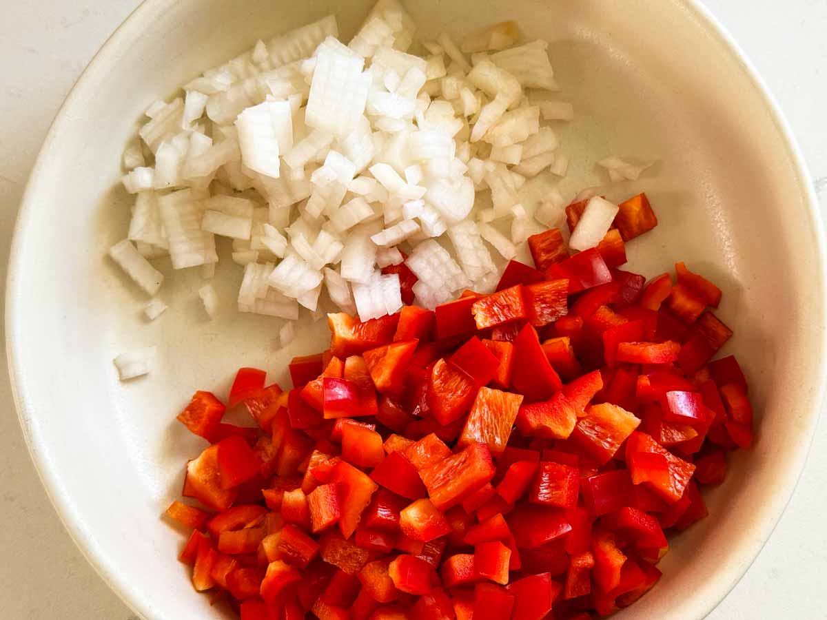 Small diced red bell pepper and onion in a bowl.