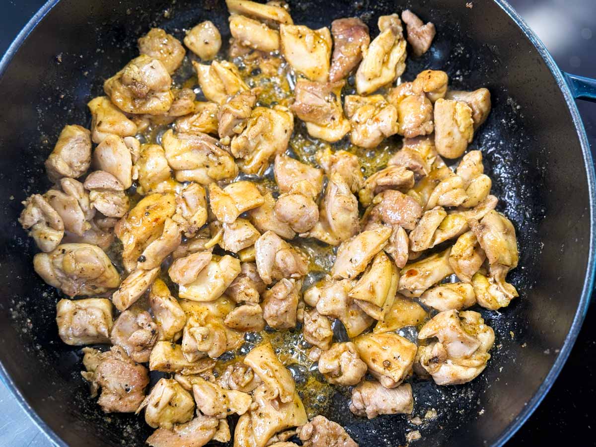 Cooked pieces of chicken thighs in a cast iron skillet.