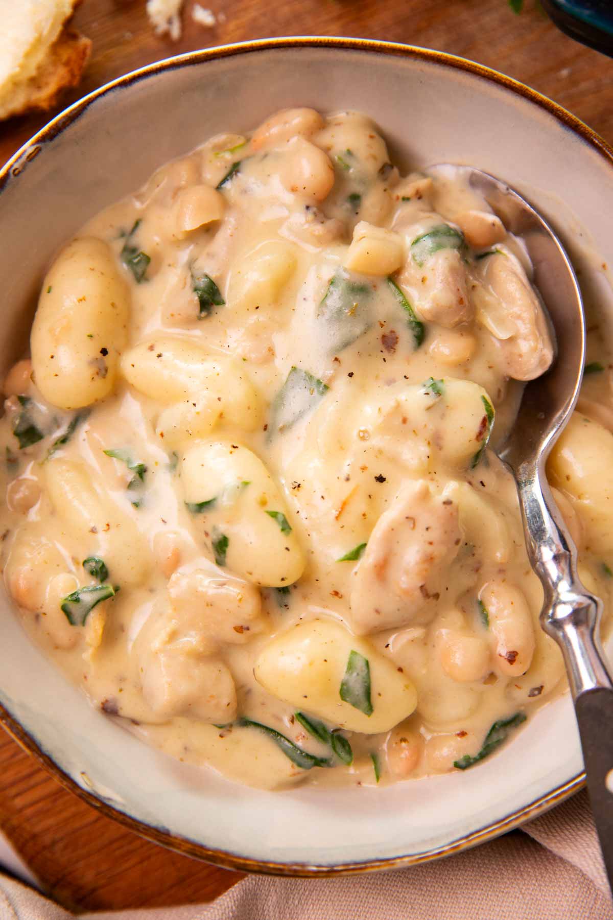Close up of a bowl with creamy chicken gnocchi and a spoon.