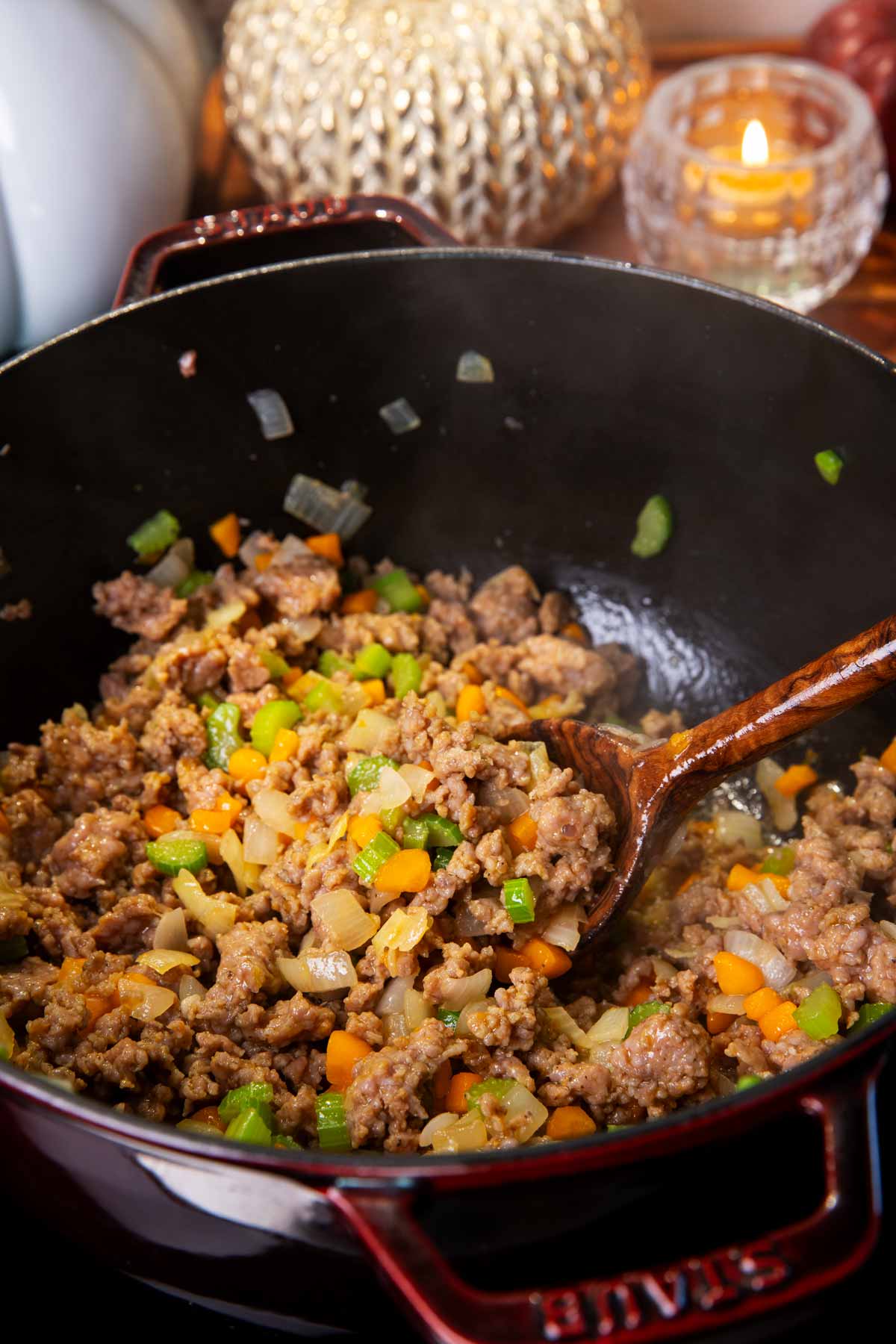 Sautéed vegetables and browned Italian sausage in a cast iron pot.