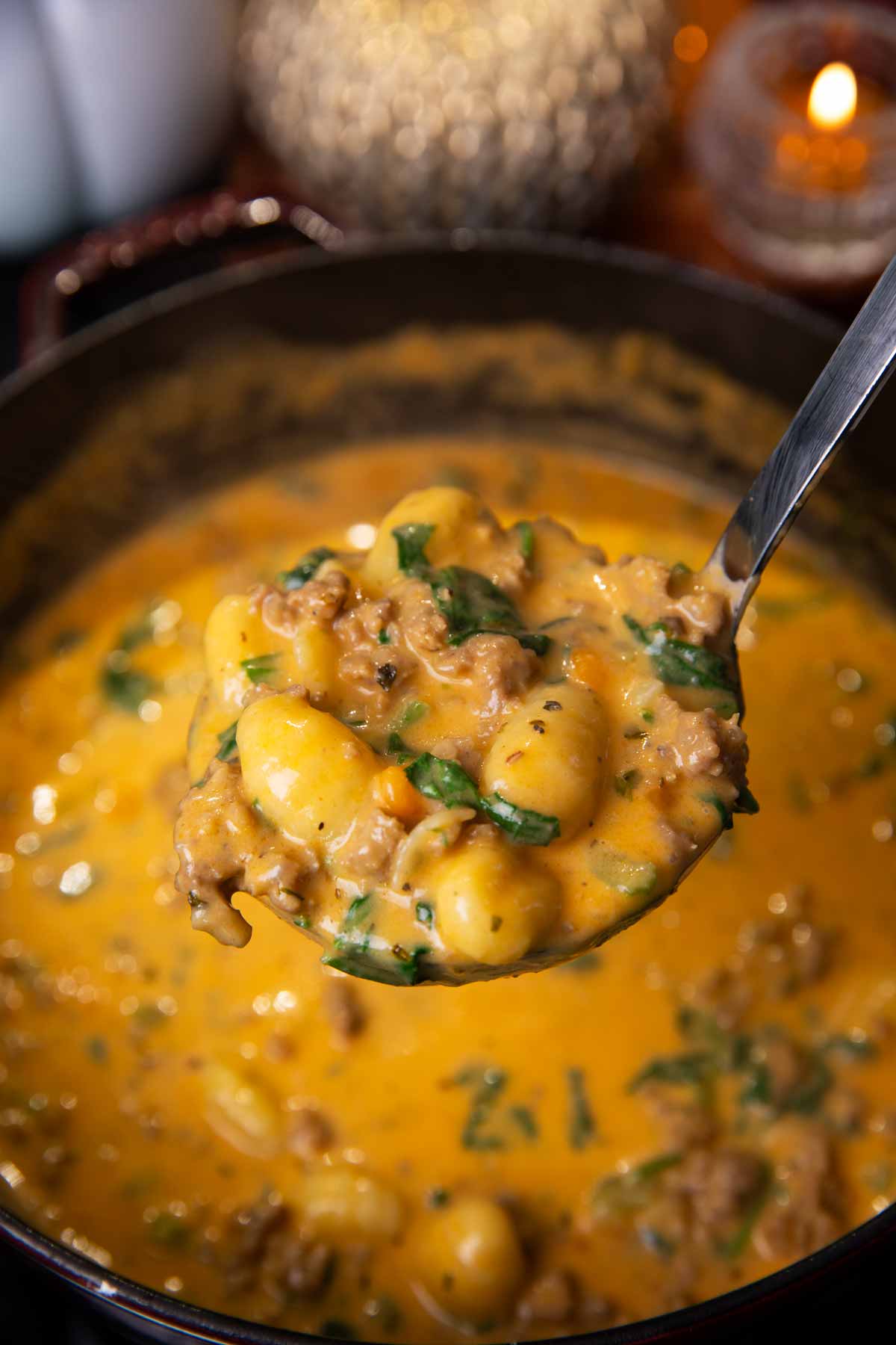 Ladle filled with sausage gnocchi soup.
