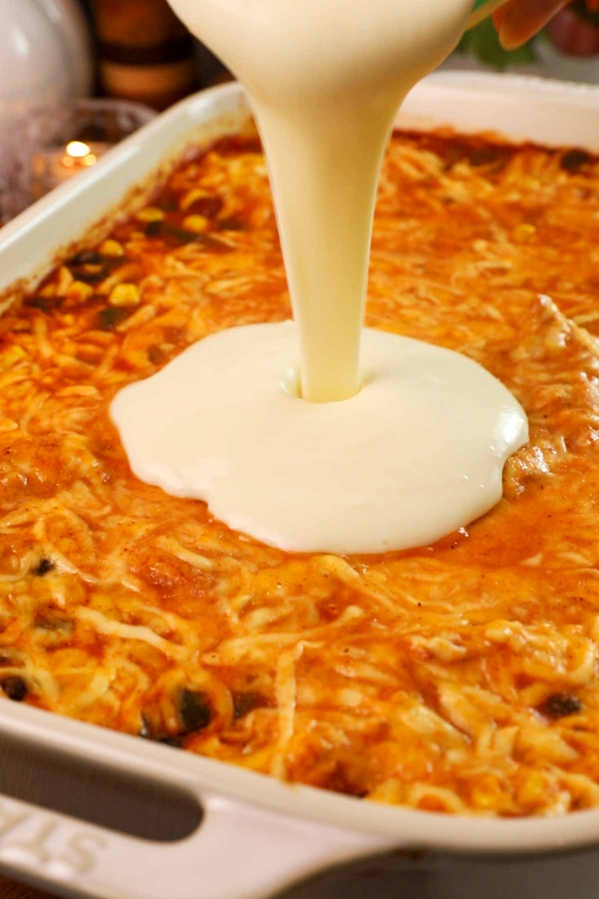 Pouring queso on a baked chicken and rice casserole.