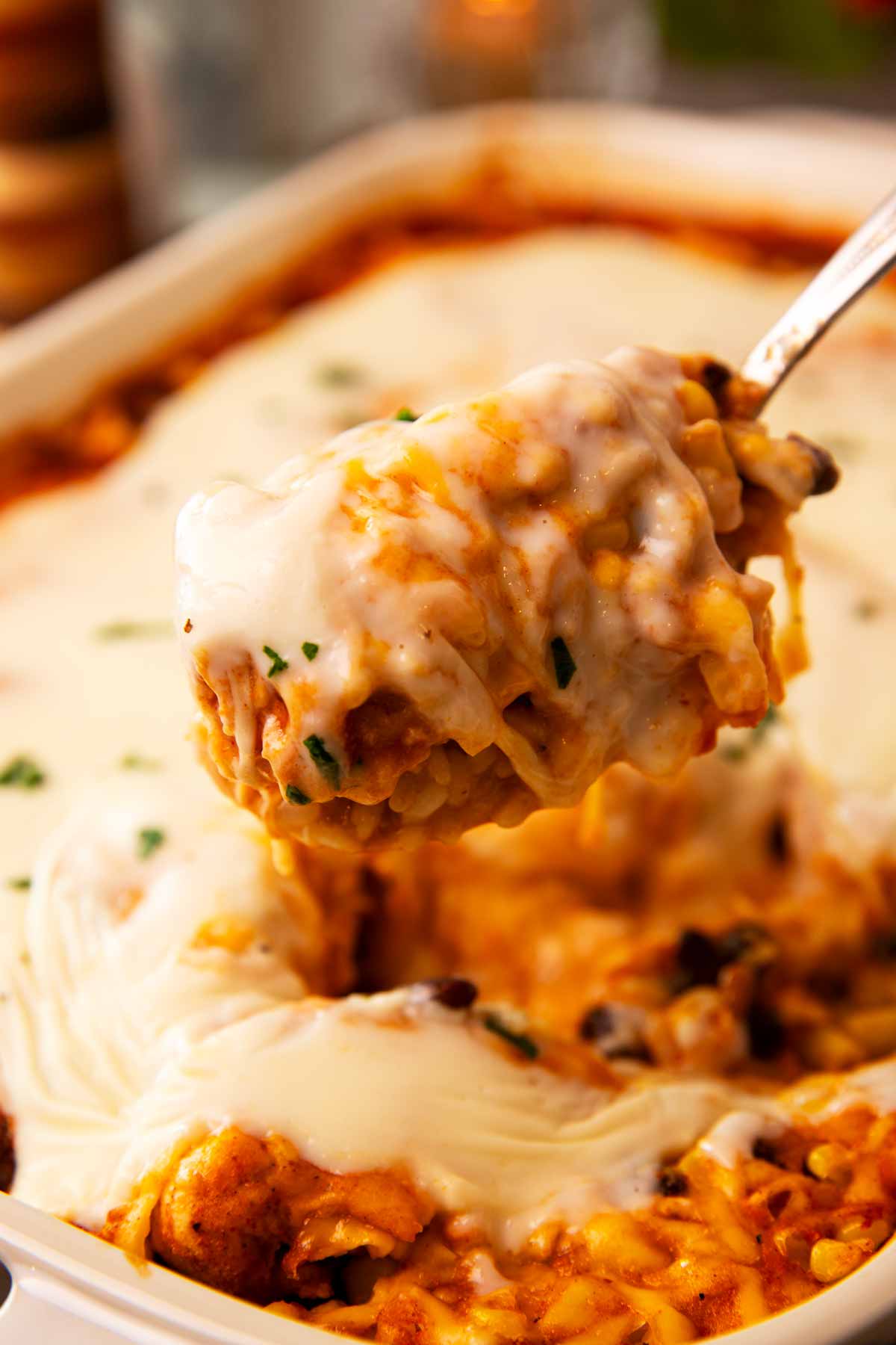 Spoon scooping chicken and rice casserole from a casserole dish.