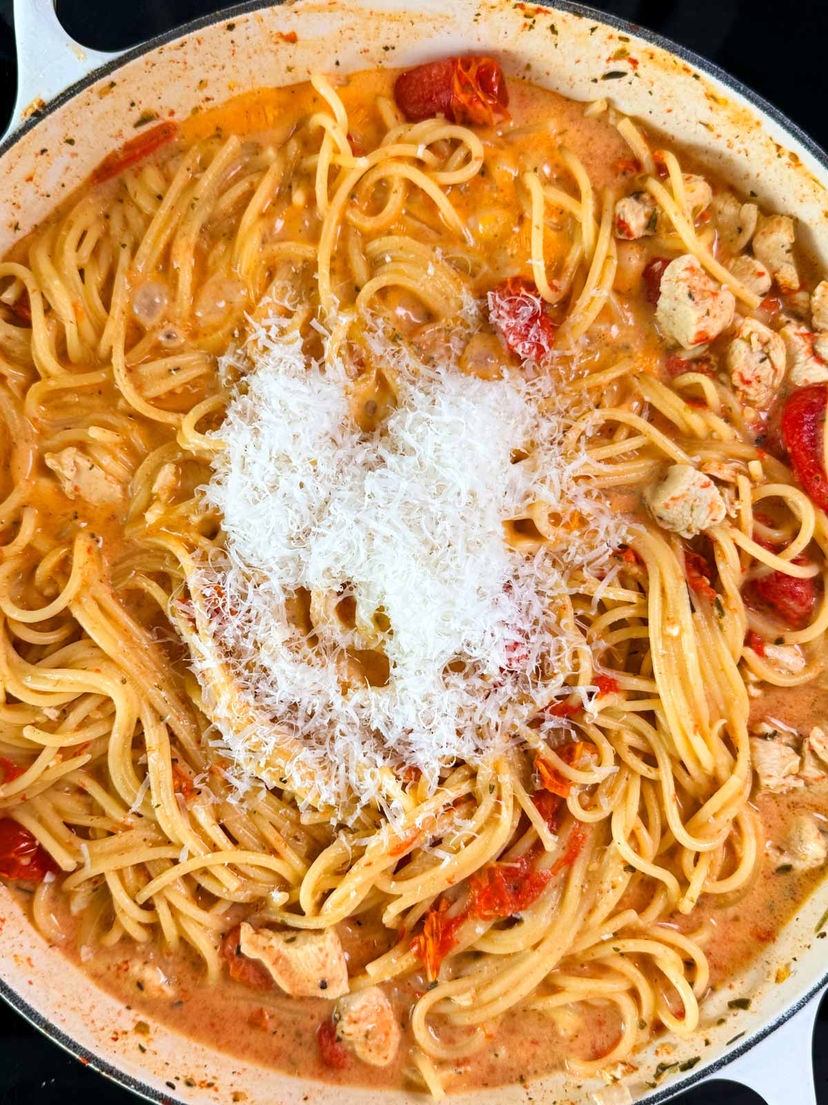 Tomato Basil Chicken Pasta in a pan with parmesan.