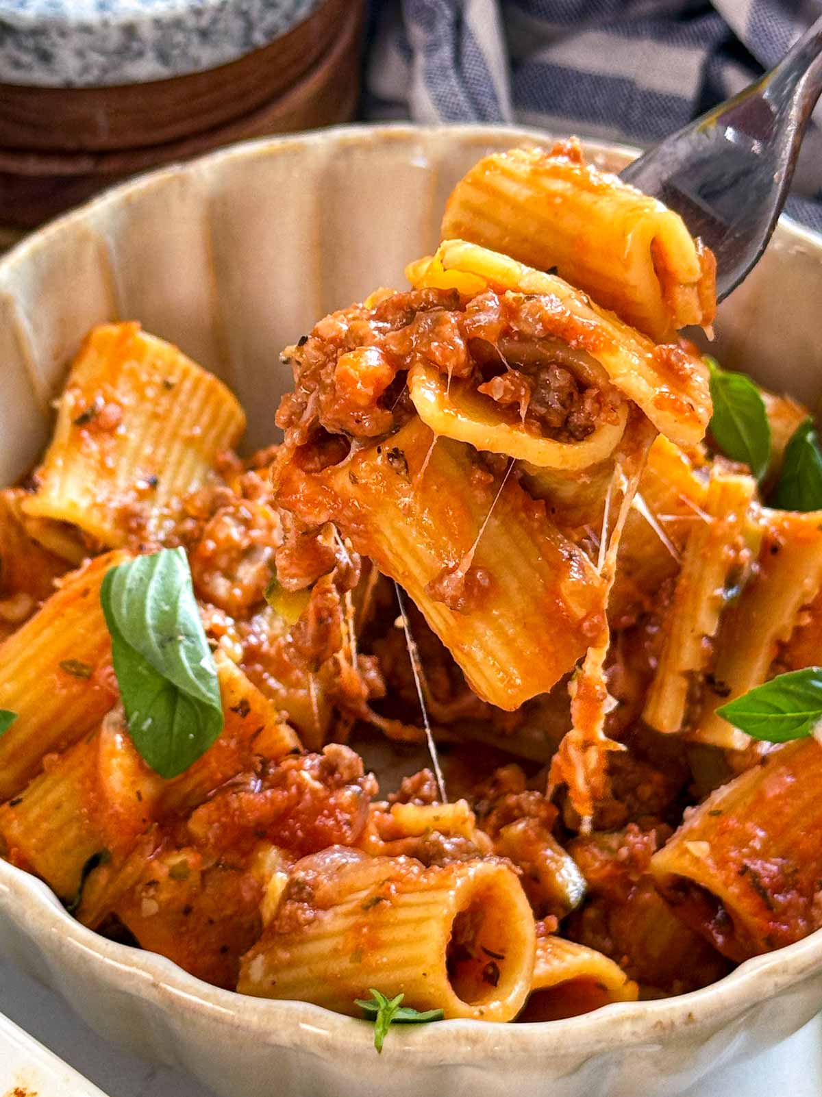 Using a fork to take ground beef pasta from a bowl.