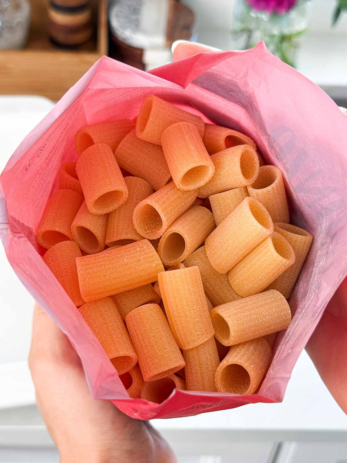 Female hand holding an opened pasta package.