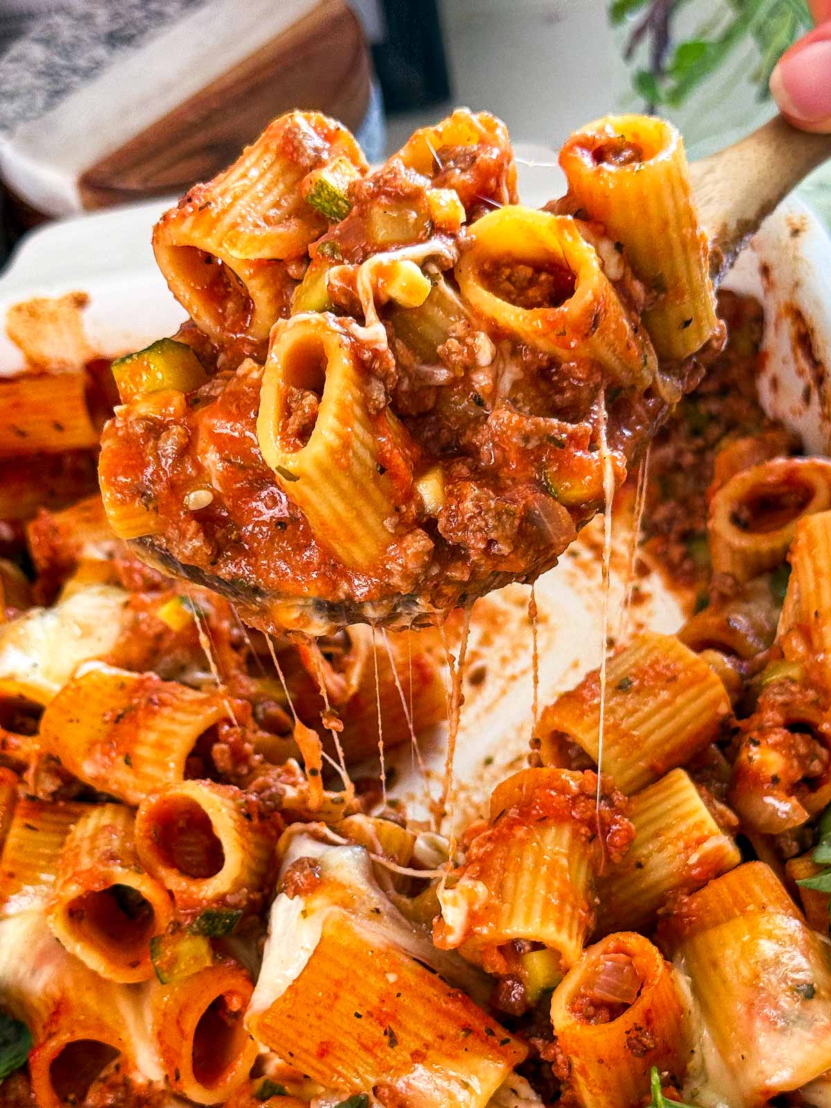 Close up scoop of ground beef and pasta casserole with cheese.