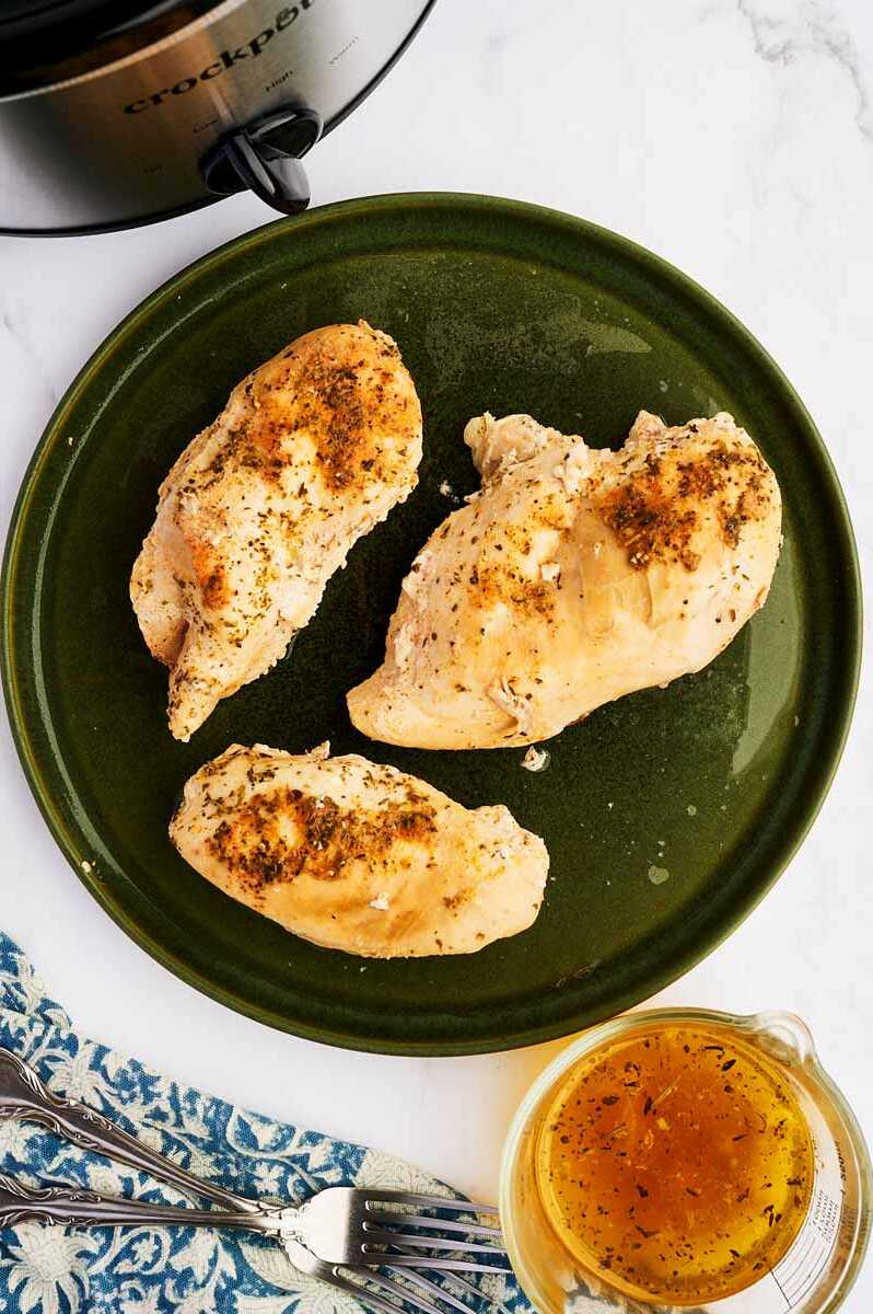Cooked chicken breast resting on a green plate.