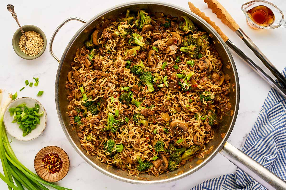 Skillet with ground beef and ramen noodles being served.