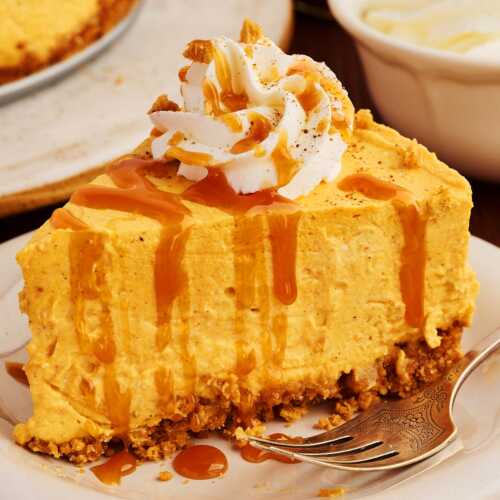 Slice of no bake pumpkin cheesecake on a plate drizzled with caramel sauce.