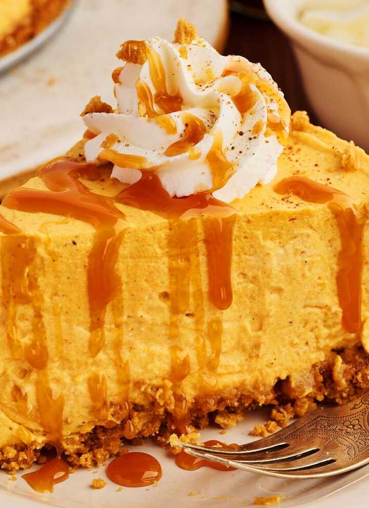 Slice of no bake pumpkin cheesecake on a plate drizzled with caramel sauce.