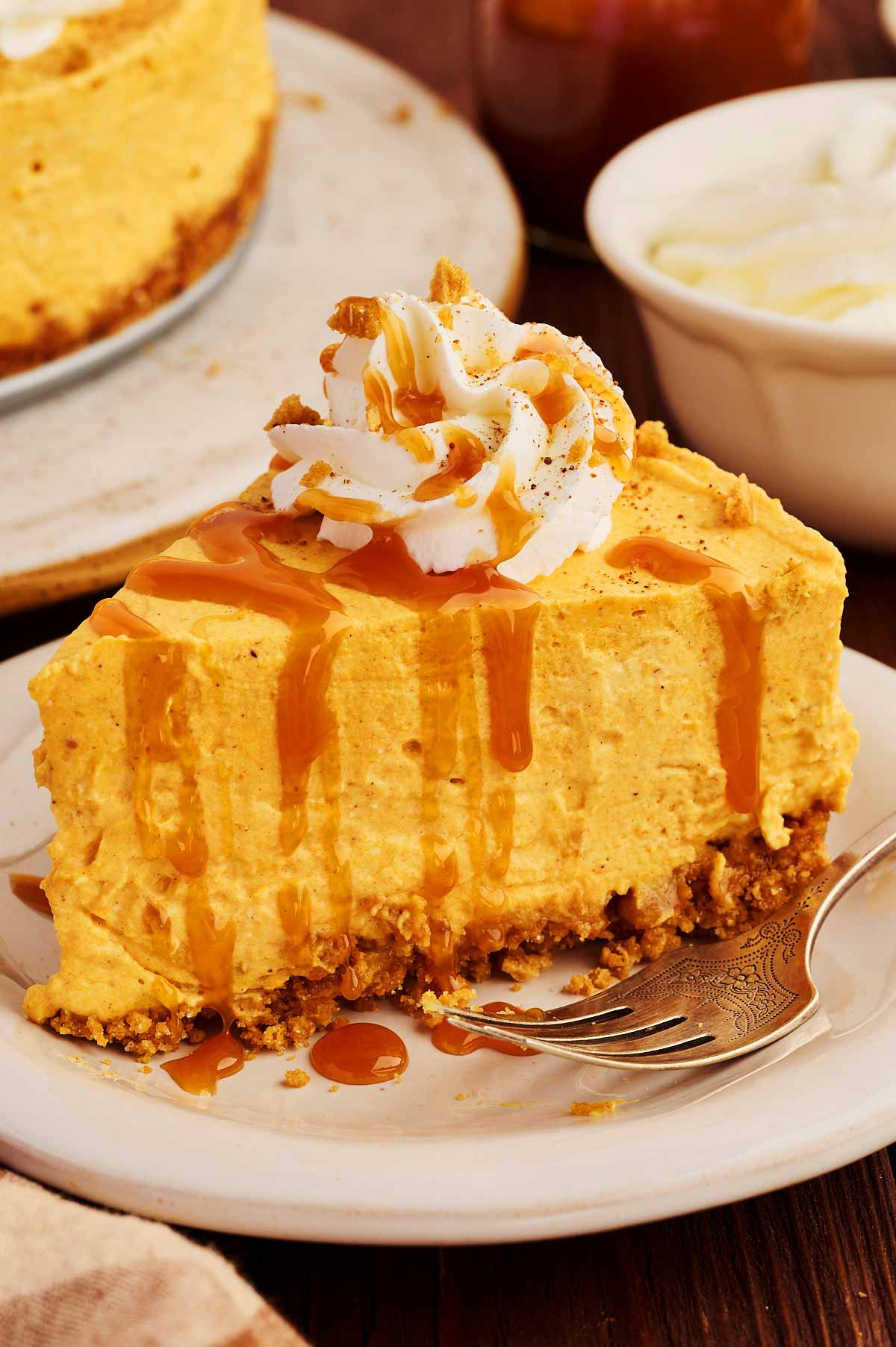 Slice of no bake pumpkin cheesecake on a plate drizzled with caramel sauce.