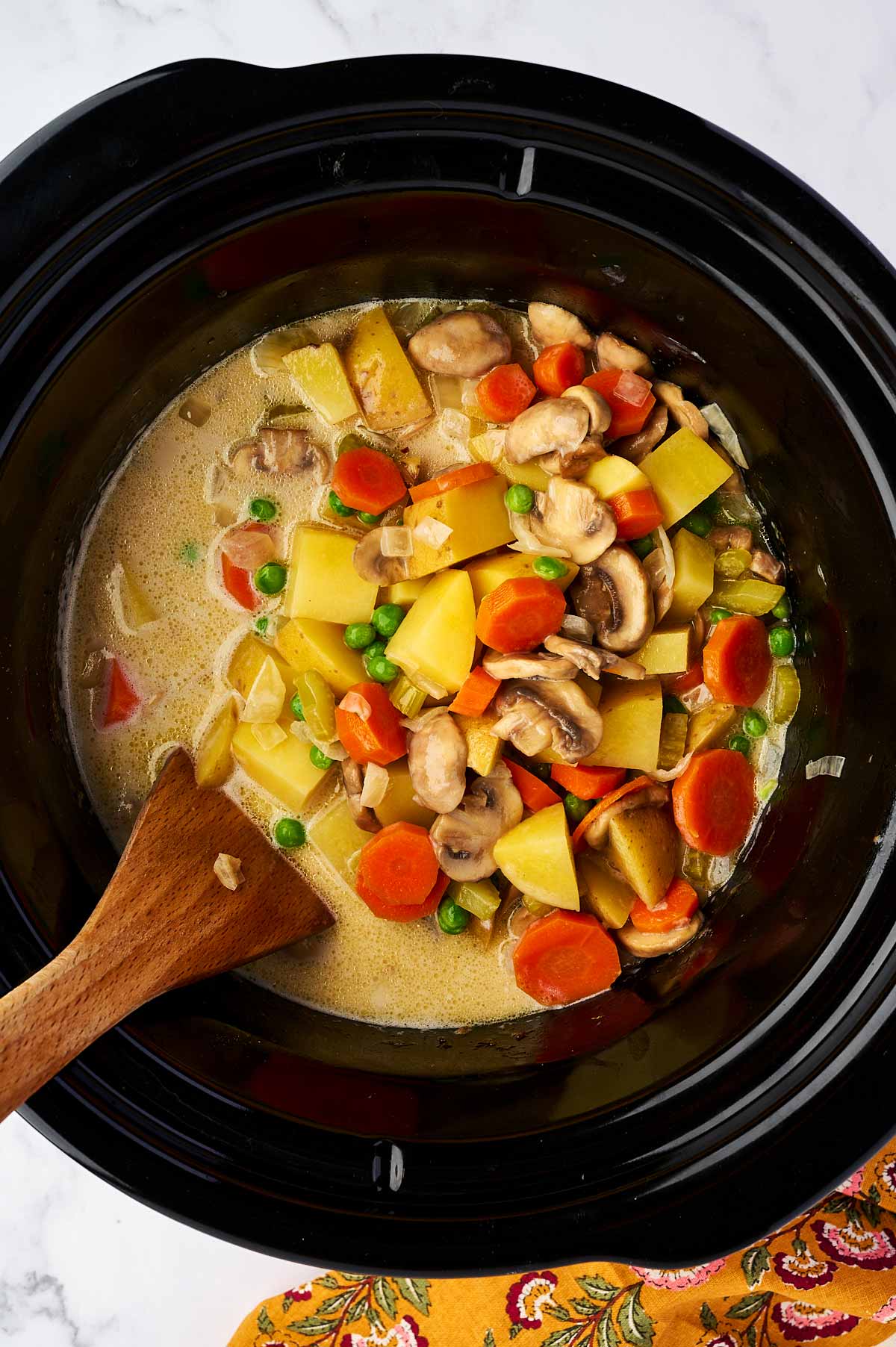 Stirring cream into vegetables in slow cooker.