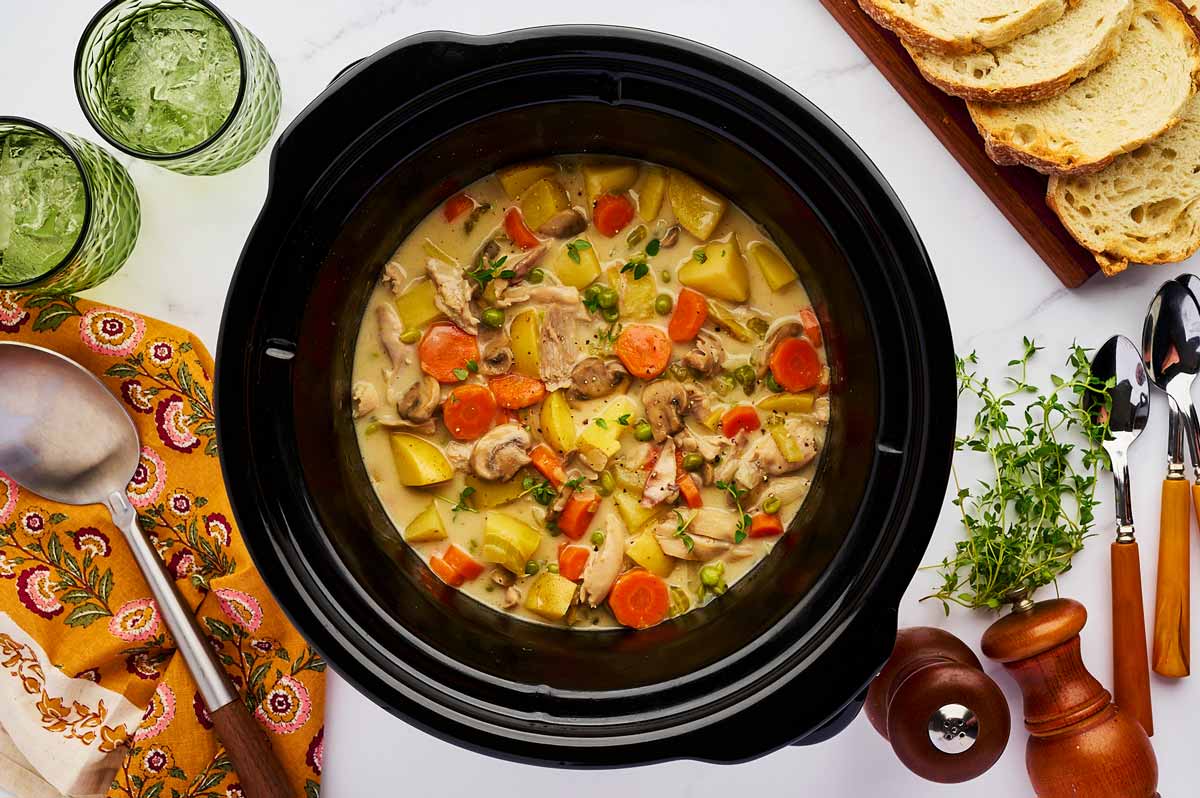 Overhead view of a slow cooker chicken stew being served with bread.