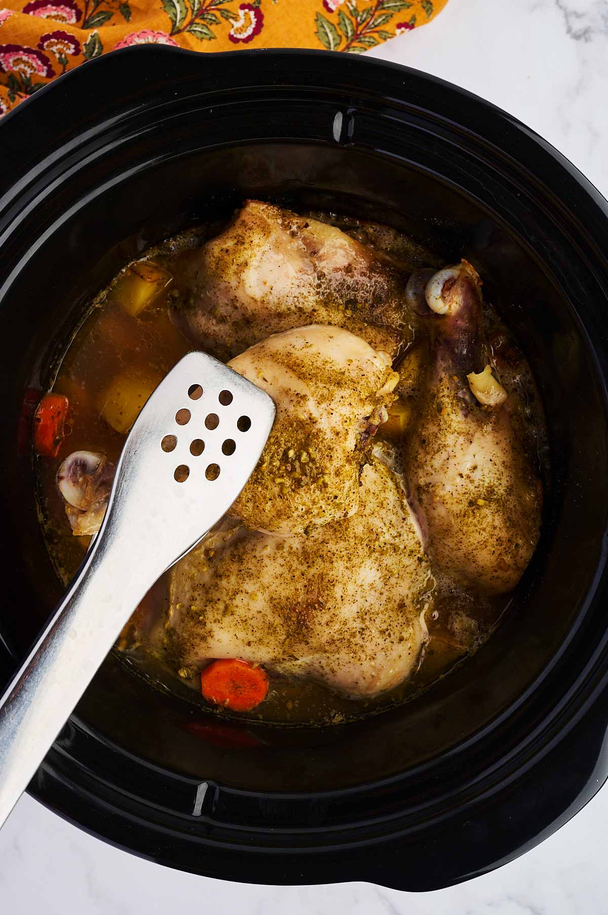 Removing cooked chicken pieces from slow cooker.