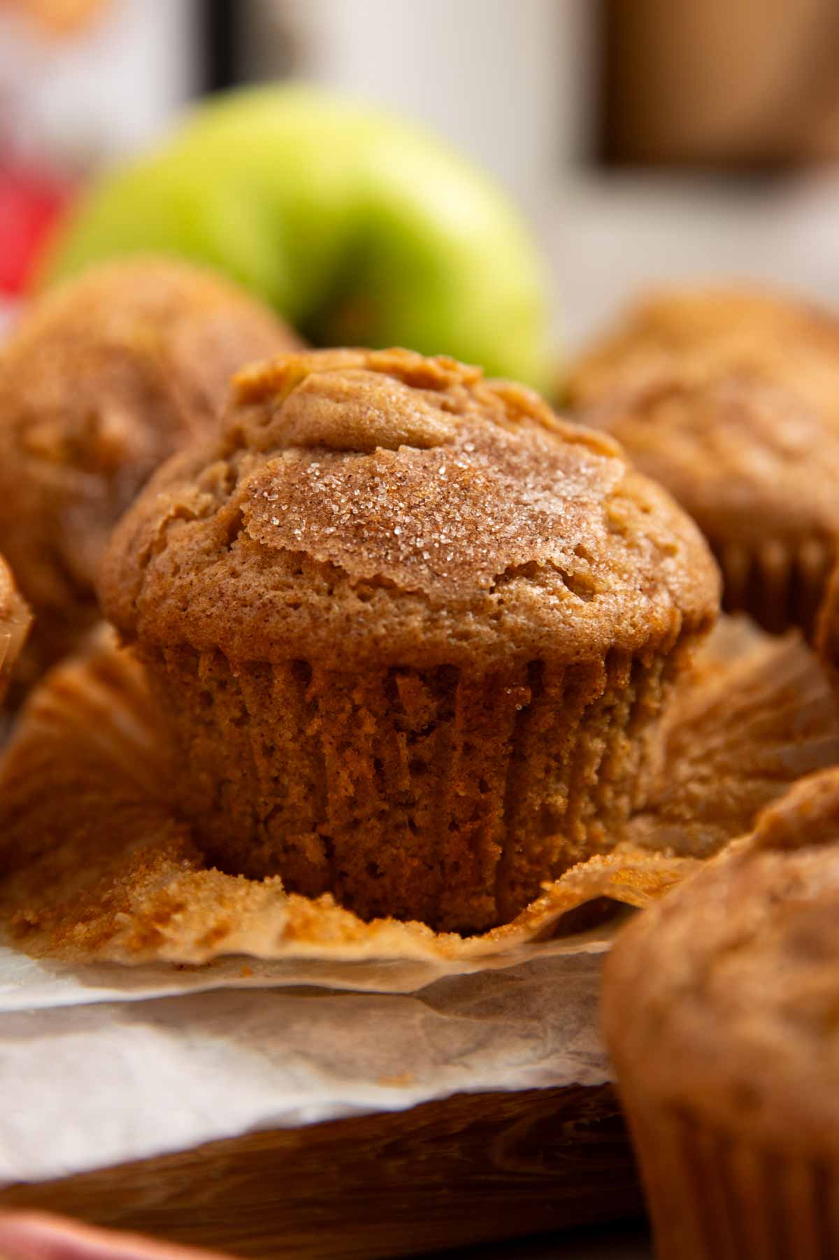 Apple muffin on a wooden board with the wrapper unwrapped.
