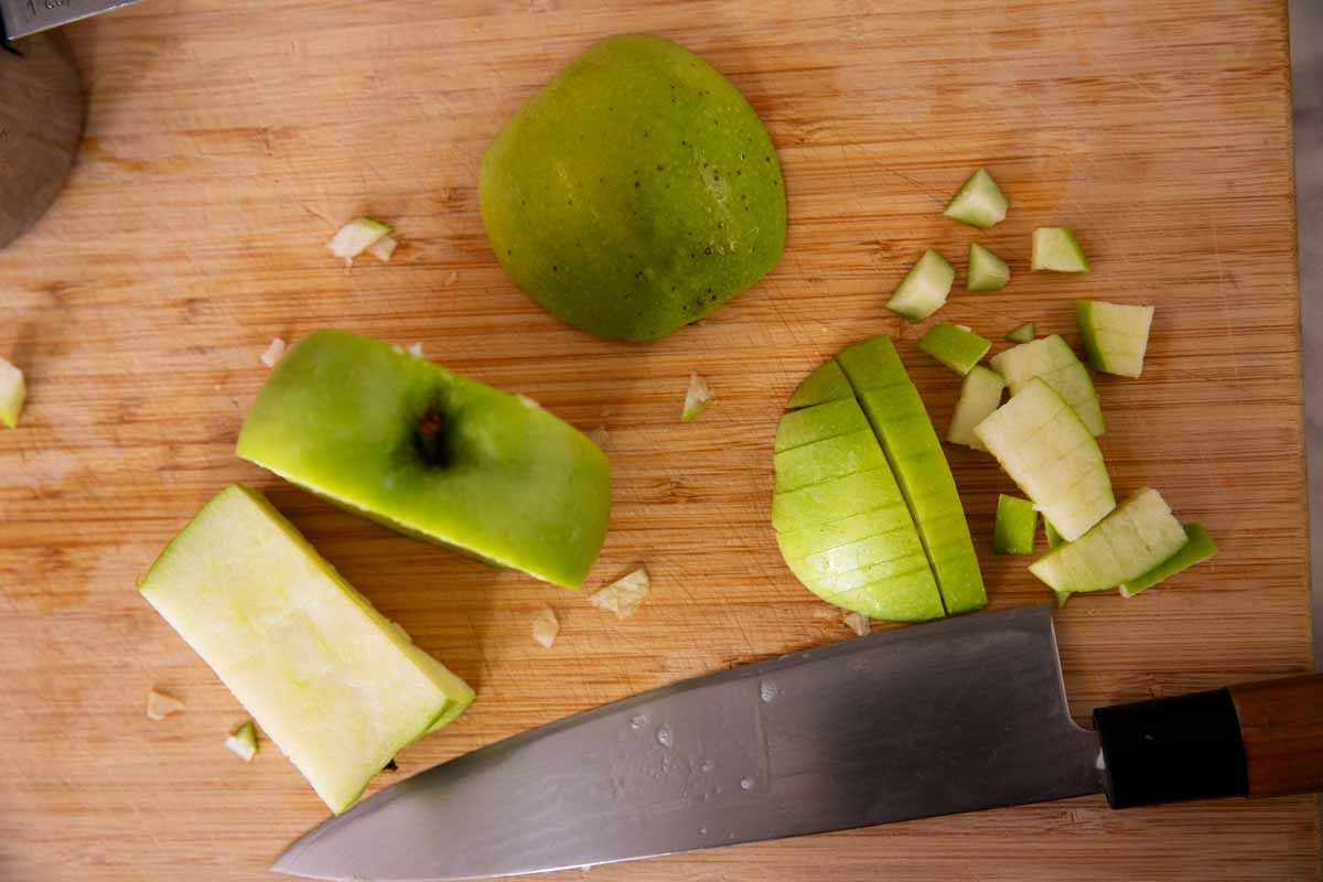Chopping up a Granny Smith apple on a wooden cutting board.