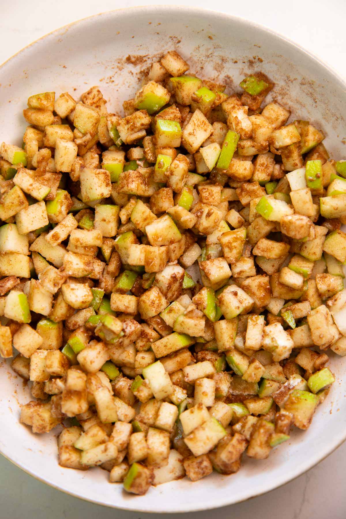 Chopped apples with cinnamon in a white bowl.