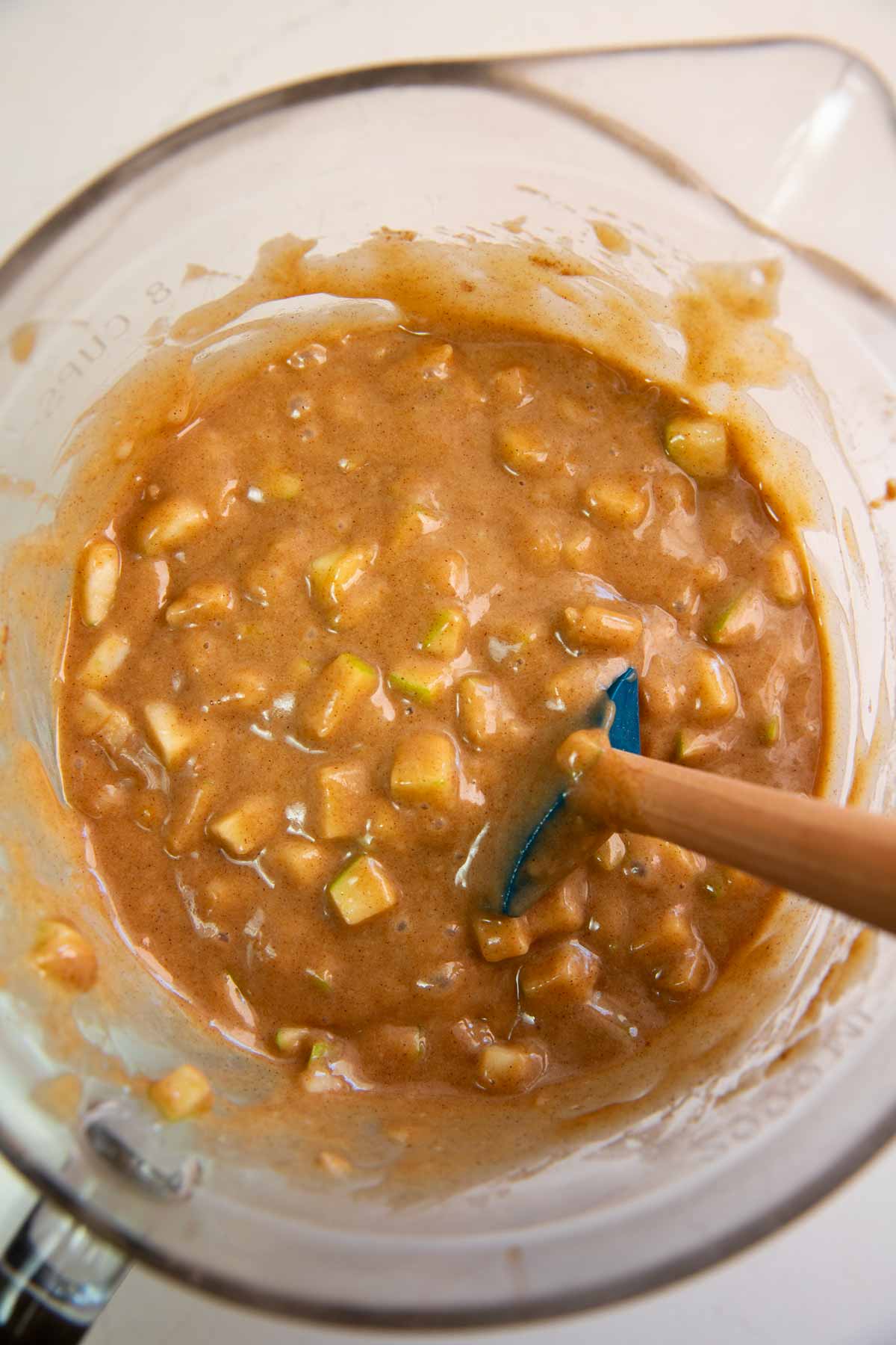 Batter for apple muffins in glass bowl.