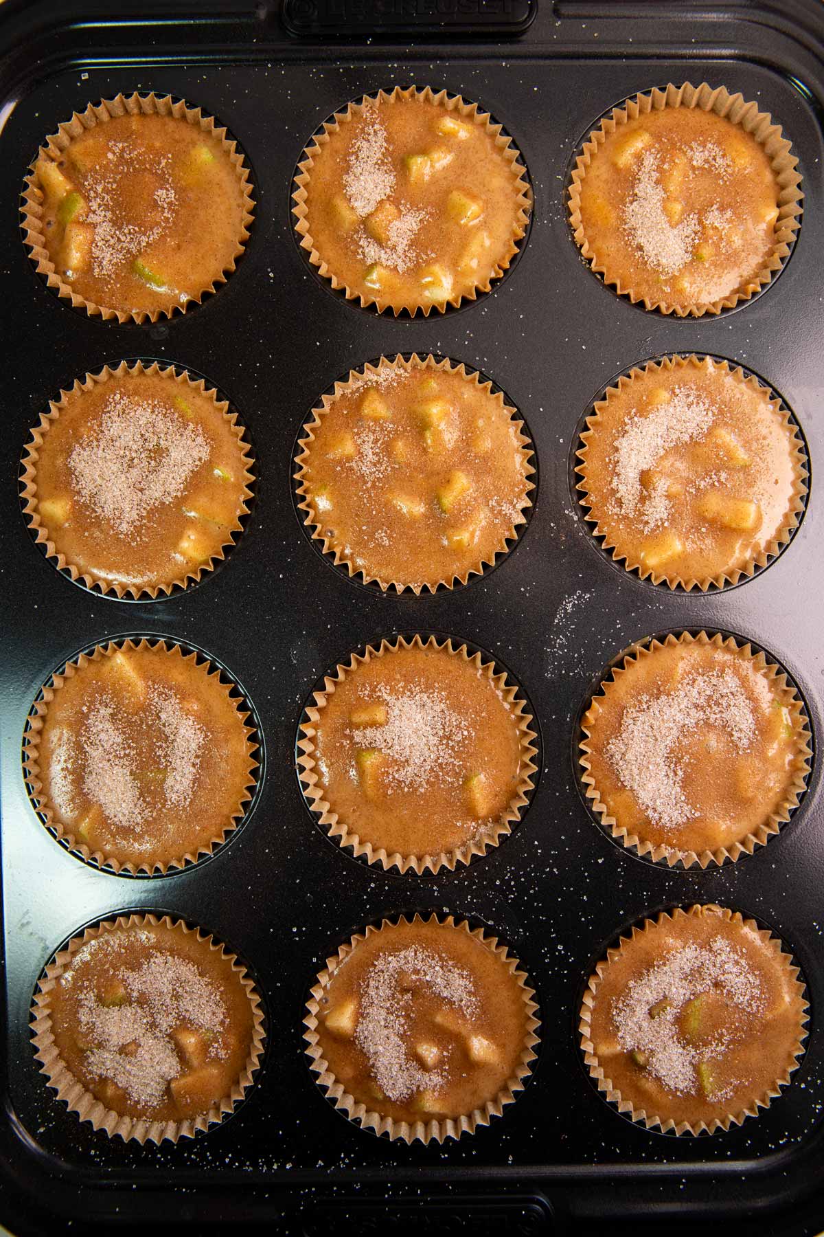 Unbaked apple muffins in a muffin pan.