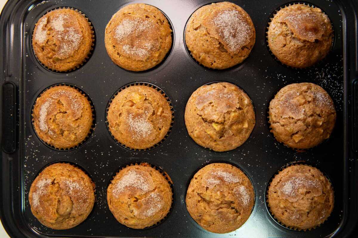 Baked apple muffins in a muffin pan.