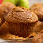 Apple muffin on a wooden board with the wrapper unwrapped.