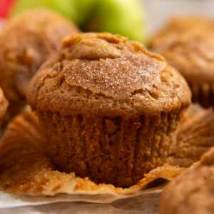 Apple muffin on a wooden board with the wrapper unwrapped.
