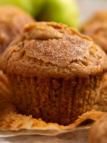Apple muffin on a wooden board with the wrapper unwrapped.