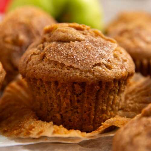 Apple muffin on a wooden board with the wrapper unwrapped.