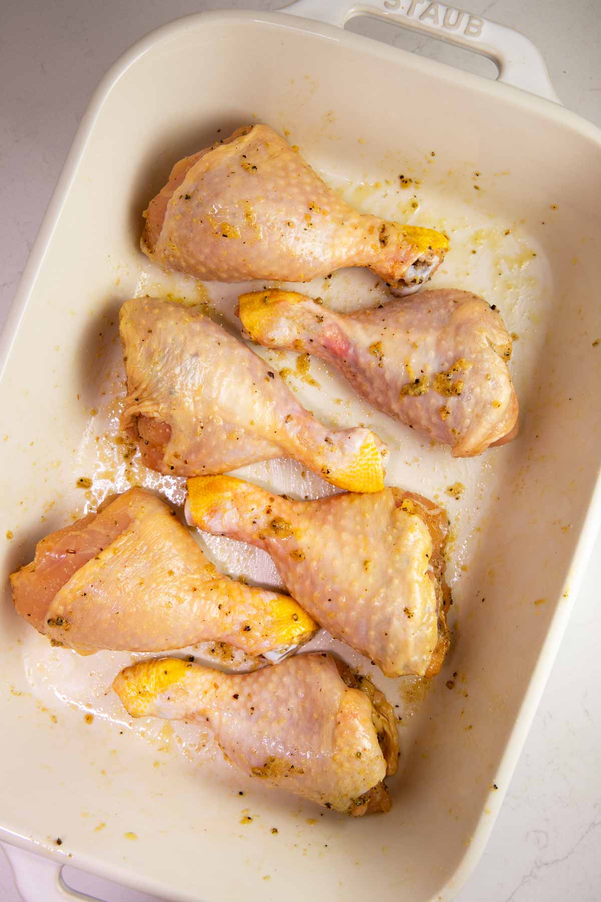Seasoned chicken legs in a casserole dish.
