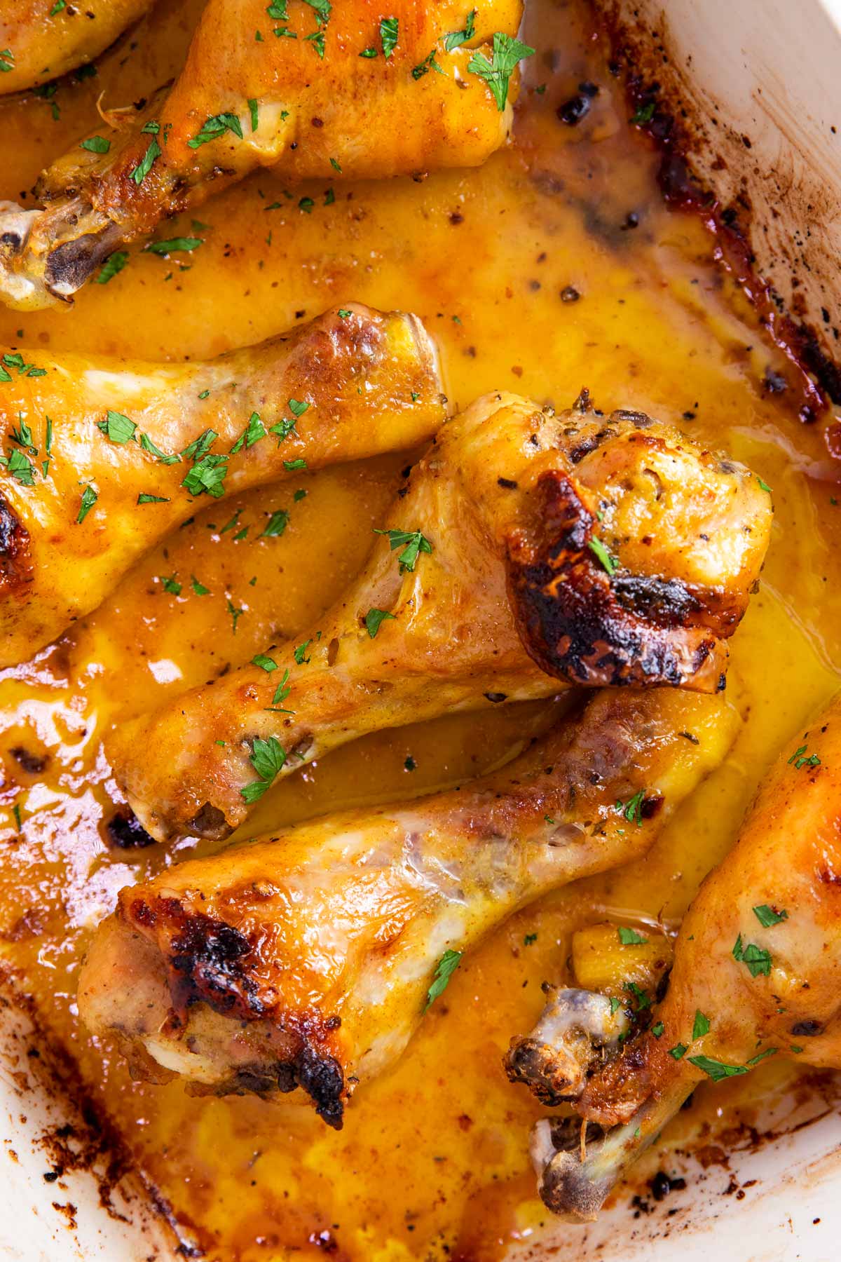 Overhead view of baked chicken legs in a white casserole dish.
