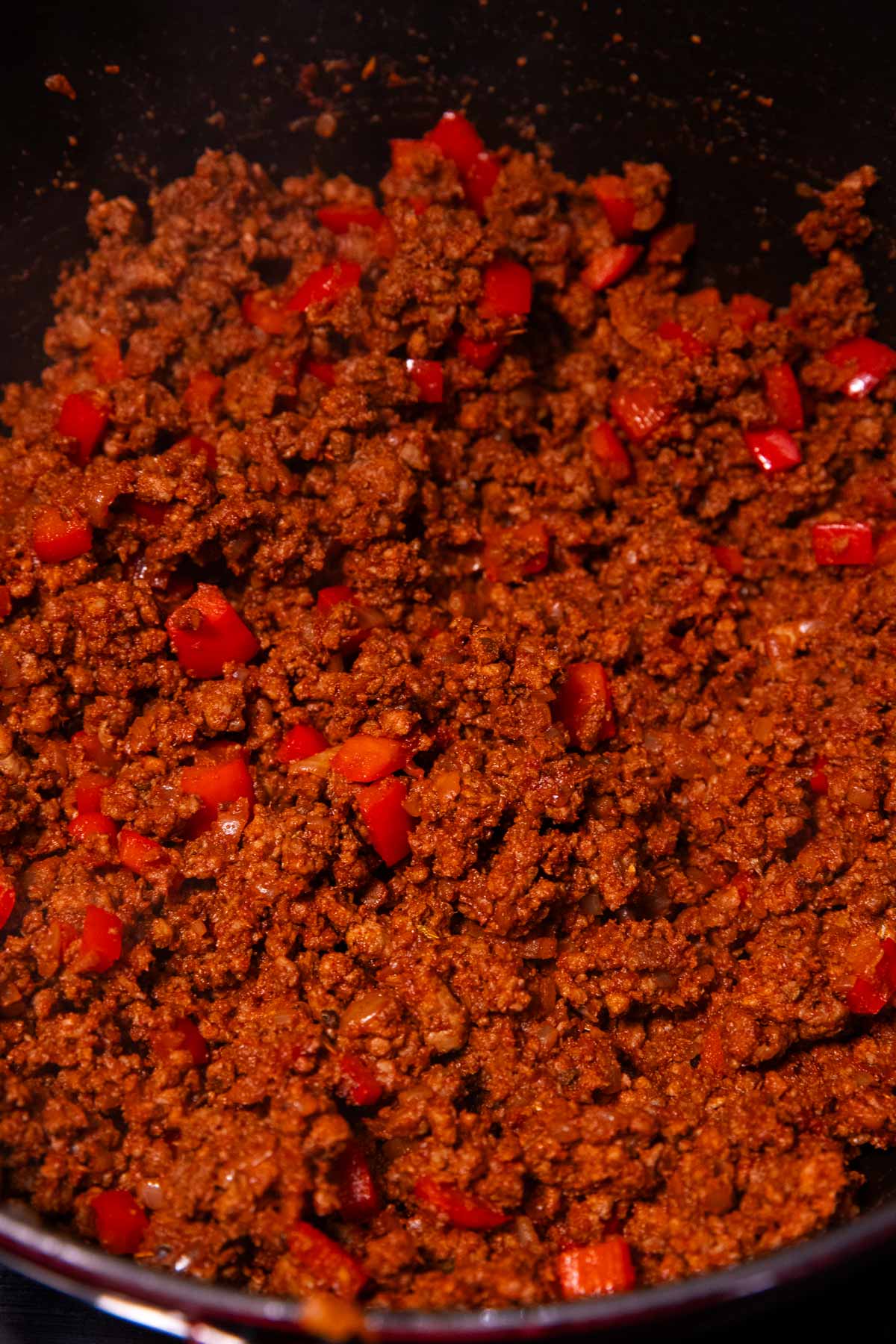 Browned ground beef with seasoning in cast iron pot.