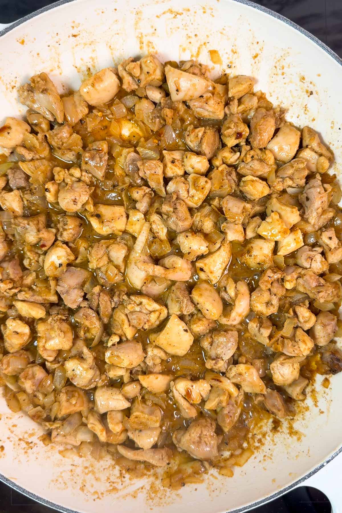 Seared bite-sized chicken thighs in a white pan.