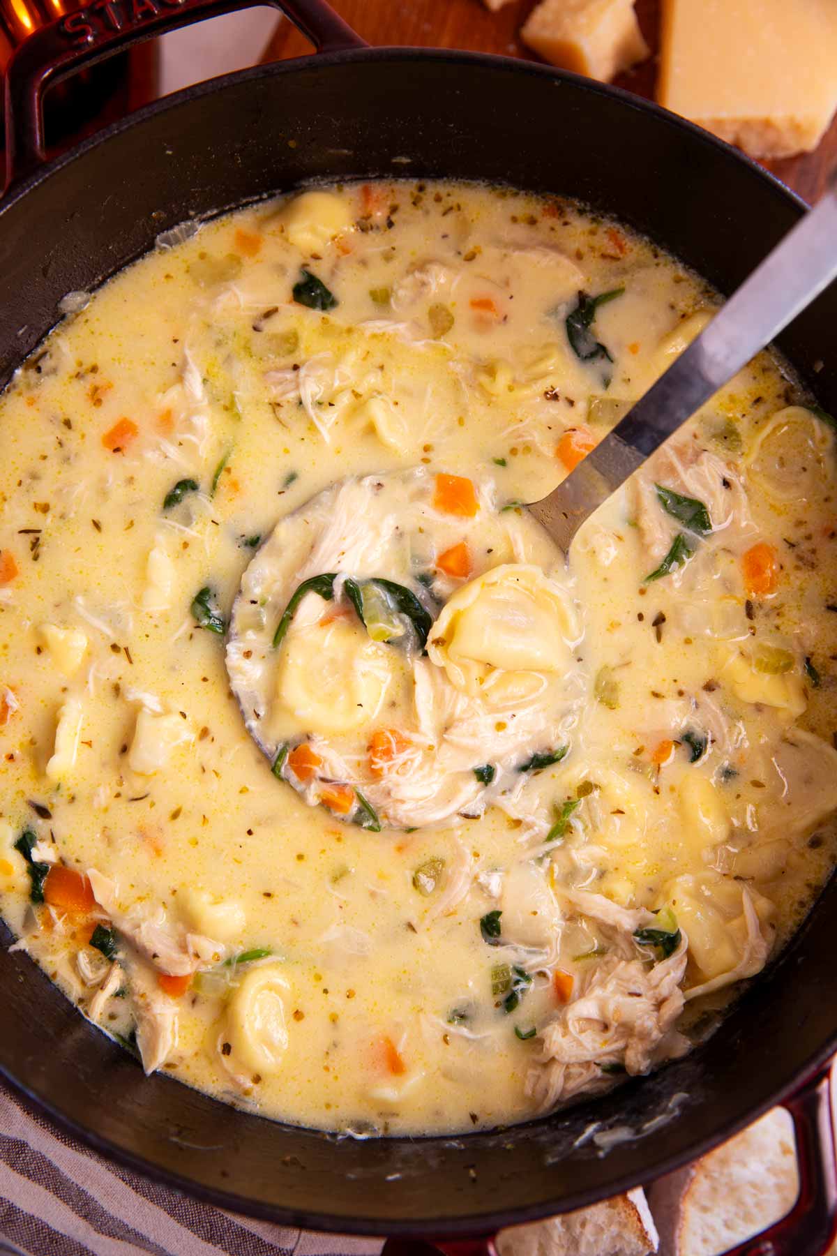 Pot with ladle scooping out creamy chicken tortellini soup.